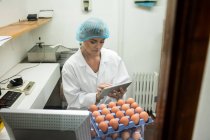 Female staff using digital tablet while working in egg factory — Stock Photo