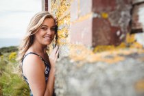 Portrait of smiling woman leaning on wall at cliff — Stock Photo