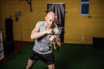 Handsome muscular Thai boxer practicing boxing in gym — Stock Photo
