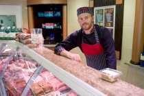 Portrait of butcher leaning on counter at butchers shop — Stock Photo