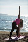 Женщина практикует йогу на пляже в солнечный день — стоковое фото