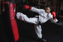 Frau übt Karate mit Boxsack im Fitnessstudio — Stockfoto
