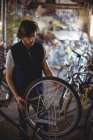 Mecánico examinando bicicleta en taller - foto de stock