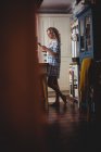 Женщина пользуется мобильным телефоном на кухне дома — стоковое фото