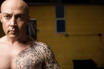 Татуированный безрубашечный тайский боксер позирует в спортзале — стоковое фото