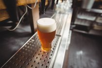 Close-up of beer glass with froth in a bar — Stock Photo