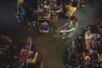 Visão geral do mecânico que examina a bicicleta na oficina — Fotografia de Stock
