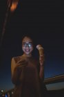 Молода жінка використовує мобільний телефон, маючи морозиво вночі — стокове фото