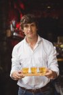 Portrait of bartender holding whisky shot glasses at bar counter in bar — Stock Photo