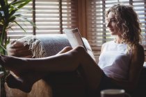 Красива жінка читає журнал у вітальні вдома — стокове фото
