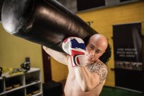 Boxer portant un sac de boxe dans un studio de fitness — Photo de stock