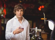 Portrait de bar tendre tenant un verre de vin rouge au comptoir du bar — Photo de stock