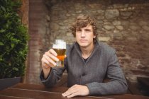 Retrato de homem segurando copo de cerveja no bar — Fotografia de Stock