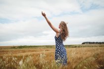 Rear view woman standing with outstretched arms in field — Stock Photo