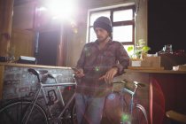 Uomo che utilizza il telefono cellulare in negozio di biciclette — Foto stock