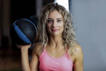 Ritratto di bella donna che tiene palla da ginnastica in palestra — Foto stock