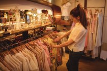Mujer seleccionando ropa en perchas en la tienda de ropa - foto de stock