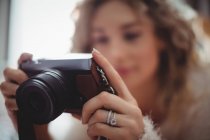 Женщина смотрит на цифровую камеру в спальне дома — стоковое фото