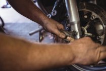 Механик, осматривающий тормоз мотоцикла в мастерской — стоковое фото