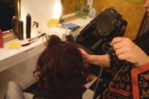 Hair stylist blow drying woman's hair at a professional salon — Stock Photo