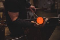 Cropped image of Glassblower shaping molten glass piece with wet cloth at glassblowing factory — Stock Photo