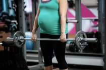 Donna incinta che lavora con il bilanciere in palestra — Foto stock