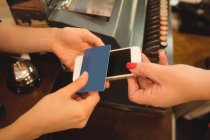 Customer giving phone and credit card to cashier at billing counter — Stock Photo
