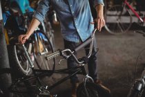 Mechaniker begutachtet Fahrrad in Werkstatt — Stockfoto