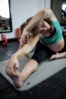 Donna incinta che esegue esercizio di stretching sul tappetino in palestra — Foto stock