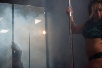 Dançarina de pólo praticando pole dance perto do espelho em estúdio — Fotografia de Stock