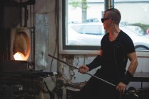 Glassblower heating glass in furnace at glassblowing factory — Stock Photo