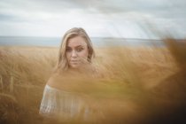 Porträt einer Frau, die an einem sonnigen Tag im Weizenfeld steht — Stockfoto
