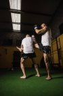 Vue à faible angle de deux boxeurs thaïlandais pratiquant la boxe dans la salle de gym — Photo de stock