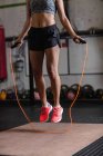 Low section of Woman exercising with skipping rope in fitness studio — Stock Photo