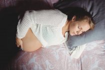 Vista superior de la mujer embarazada durmiendo en el dormitorio en casa - foto de stock