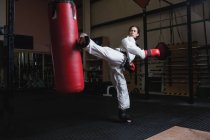 Starke Frau übt Karate mit Boxsack im Fitnessstudio — Stockfoto