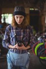 Portrait of woman adjusting vintage camera in bicycle shop — Stock Photo