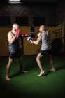 Vista lateral de dois boxers tailandeses caucasianos praticando no ginásio — Fotografia de Stock