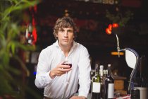 Retrato de bar concurso segurando copo de vinho tinto no balcão de bar — Fotografia de Stock