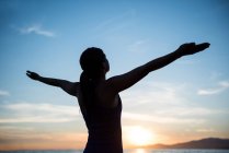 Donna che esegue yoga sulla spiaggia durante il tramonto — Foto stock