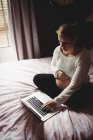 Femme enceinte utilisant un ordinateur portable dans la chambre à coucher à la maison — Photo de stock