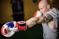 Selective focus of handsome Thai boxer practicing boxing in gym — Stock Photo