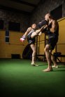 Vue à faible angle de deux boxeurs thaïlandais pratiquant la boxe dans la salle de gym — Photo de stock