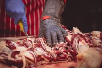 Hände des Metzgers schneiden rotes Fleisch in Metzgerei — Stockfoto