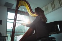 Внимательная женщина, играющая на арфе в музыкальной школе — стоковое фото