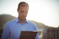 Бизнесмен с помощью цифрового планшета, стоя на балконе в офисе — стоковое фото