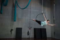 Mujer joven realizando gimnasia en el aro en el gimnasio - foto de stock