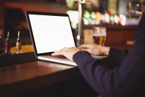 Крупним планом людина використовує ноутбук за барною стійкою — стокове фото