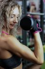 Beautiful woman lifting dumbbell at gym — Stock Photo