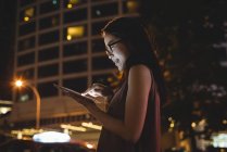 Junge Frau nachts mit digitalem Tablet auf der Straße — Stockfoto